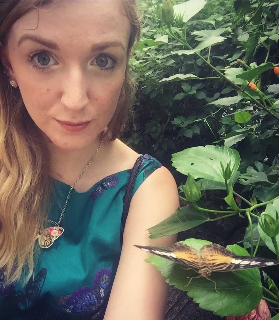 A selfie of Rachel wearing a blue dress next to a brown/gold butterfly