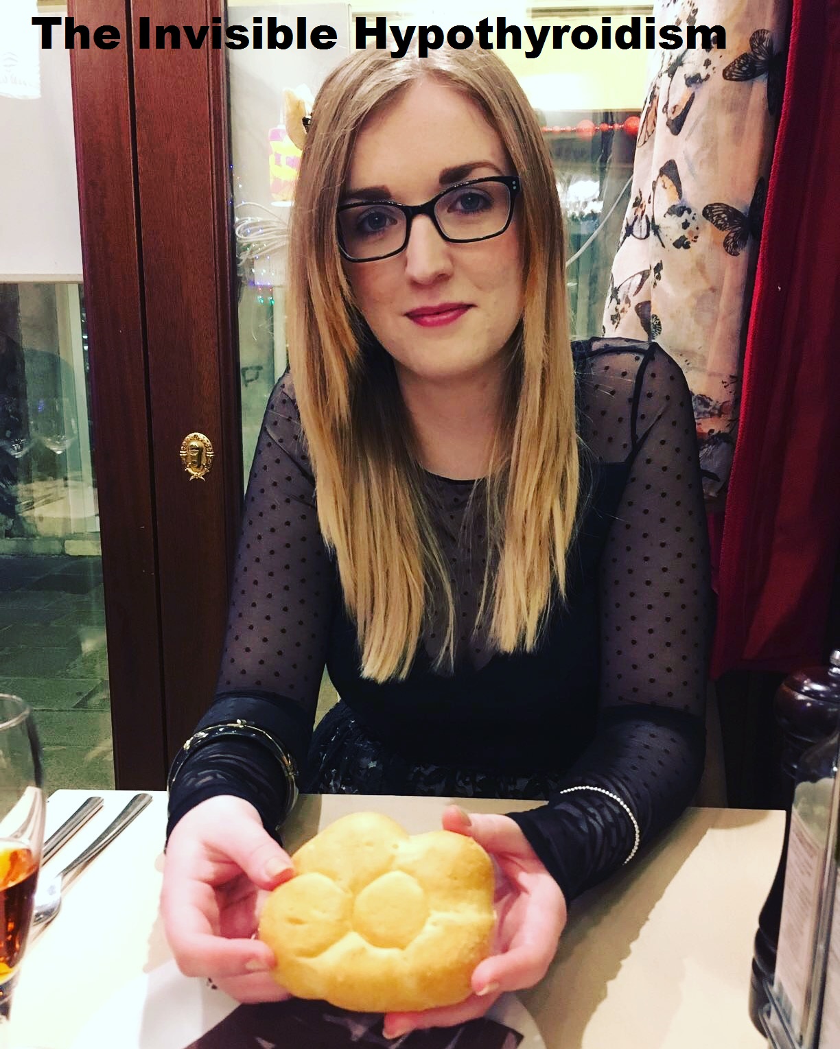 A photo of Rachel sat in a restaurant holding a gluten free bread roll
